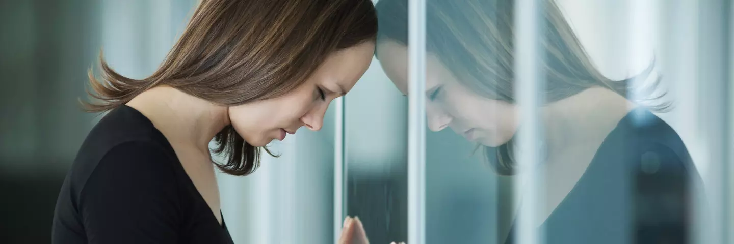 Frau lehnt den Kopf ans Fenster