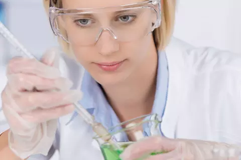 Laborantin mit Schutzbrille und Pipette